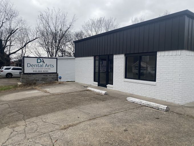 A white brick building with a black roof and a sign that says da dental arts.