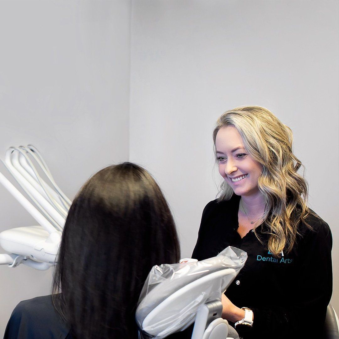 A woman is talking to another woman in a dental chair.