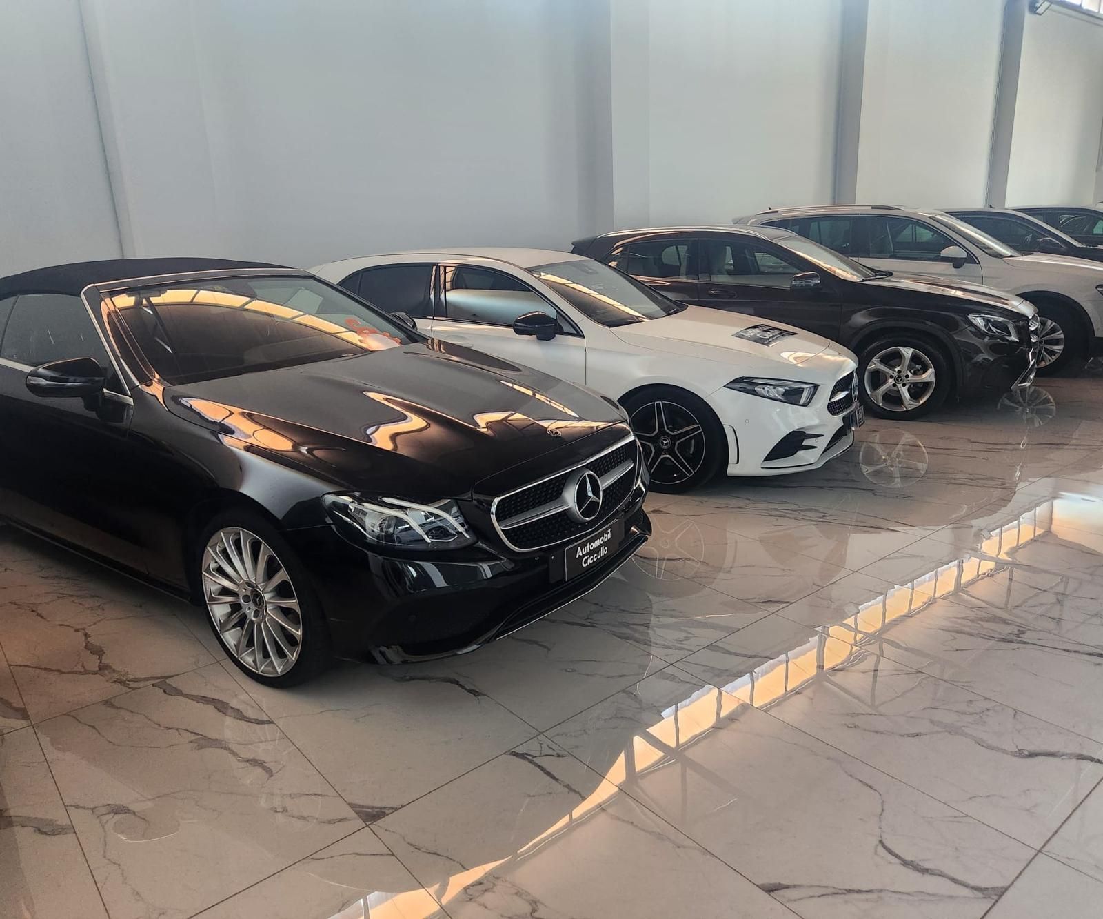 un'auto nera è parcheggiata sul lato di una strada vicino all'oceano al tramonto.