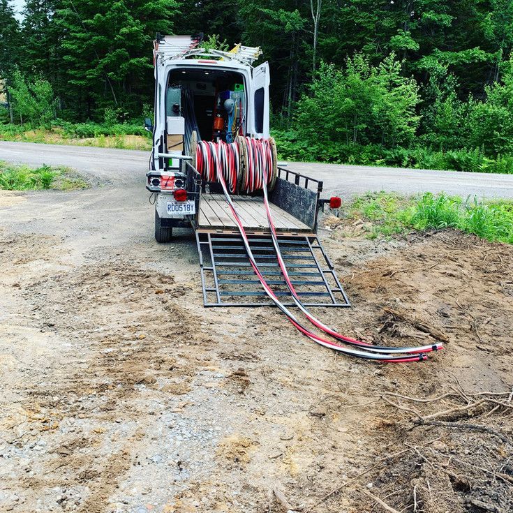 Une camionnette blanche avec un rouleau de fils électriques