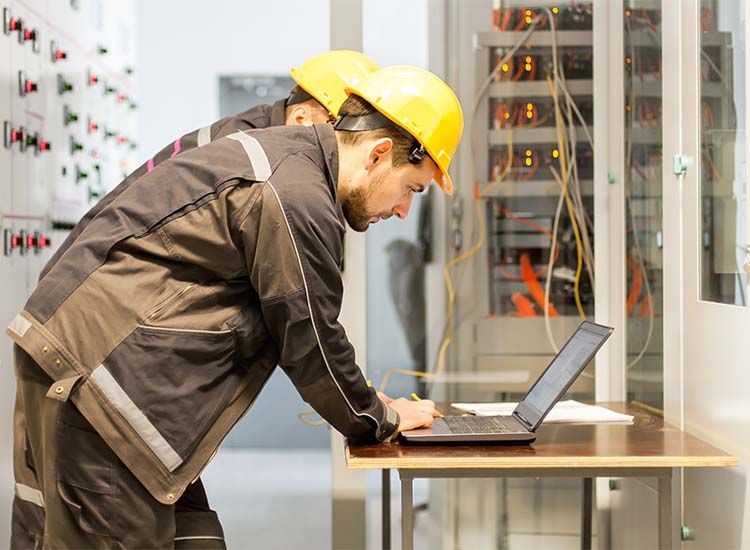 Deux hommes travaillent sur un ordinateur portable dans une salle de serveurs.