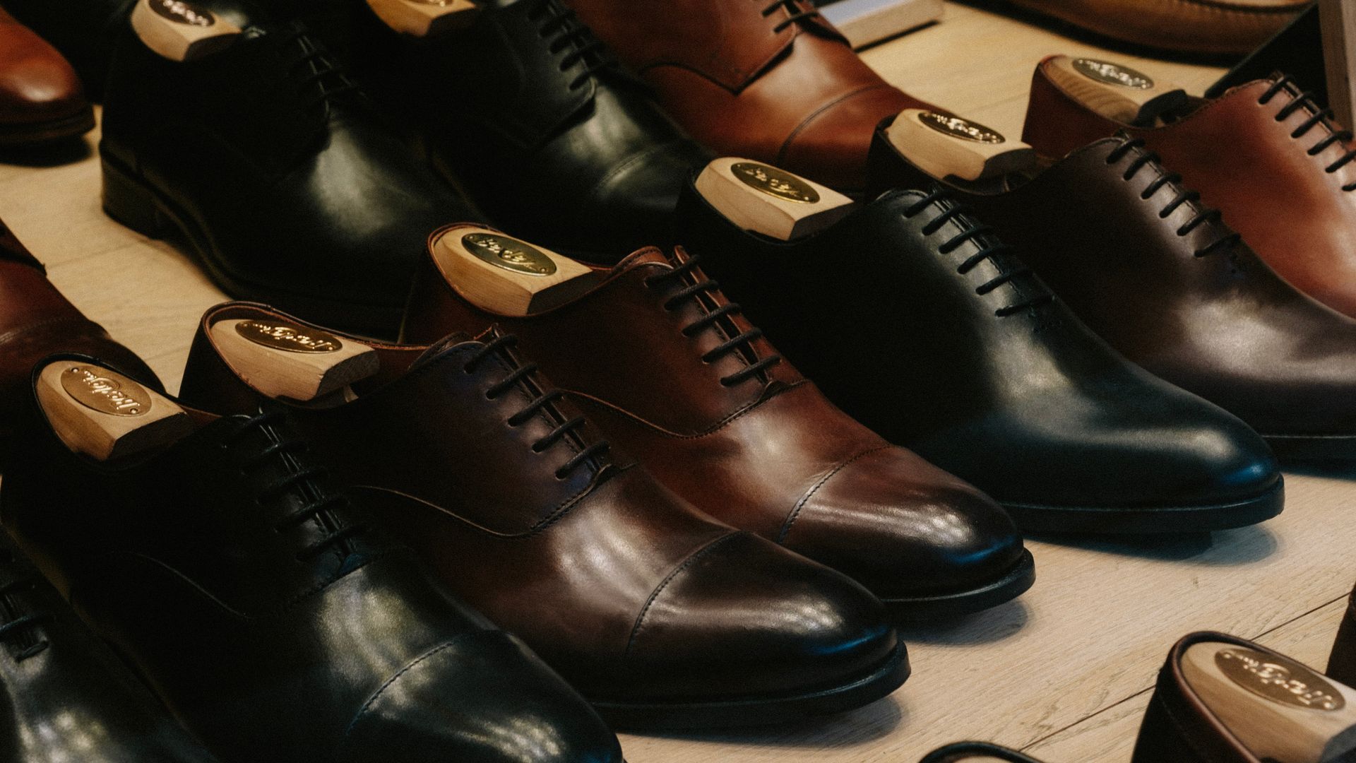 Rows of polished leather dress shoes in black and brown, displayed in a store.