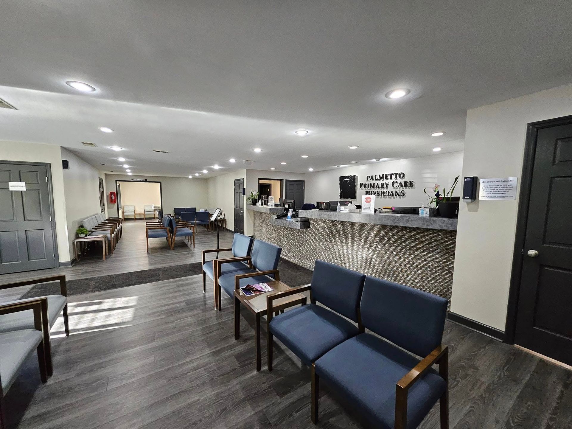 A waiting room with blue chairs and a counter in a hospital.