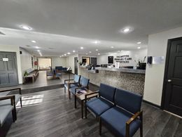 A waiting room with blue chairs and a counter in a hospital.