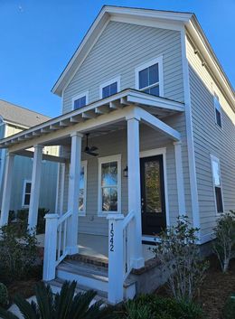 A small house with a porch and stairs on a sunny day.