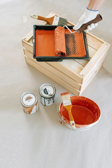 A person is painting a wooden box with a paint roller.