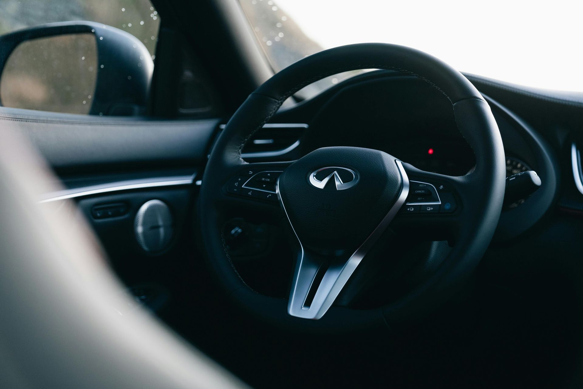 Interior of a car featuring a black steering wheel with silver accents and dashboard.