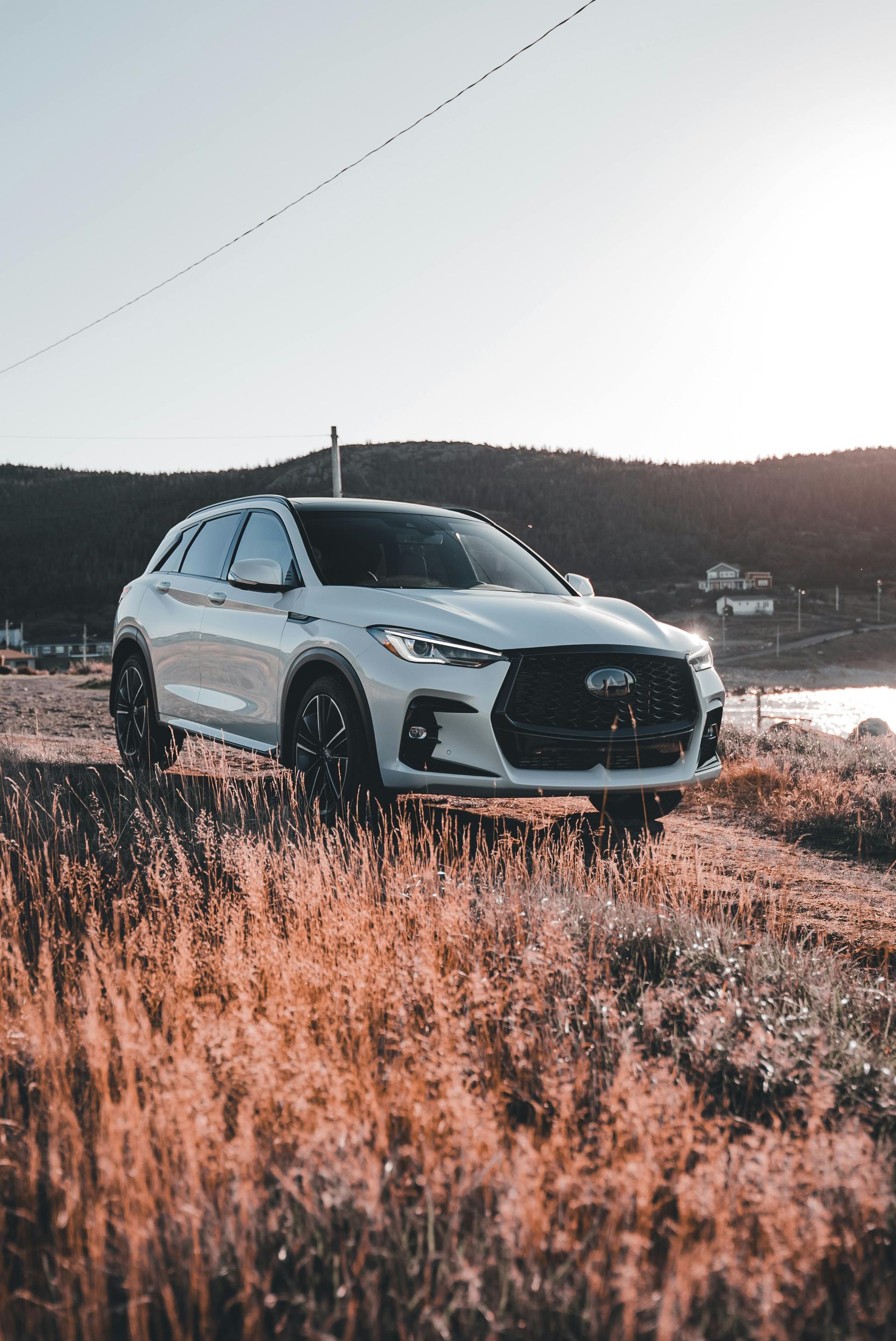 White SUV parked on a roadside, against a coastal backdrop in warm light.