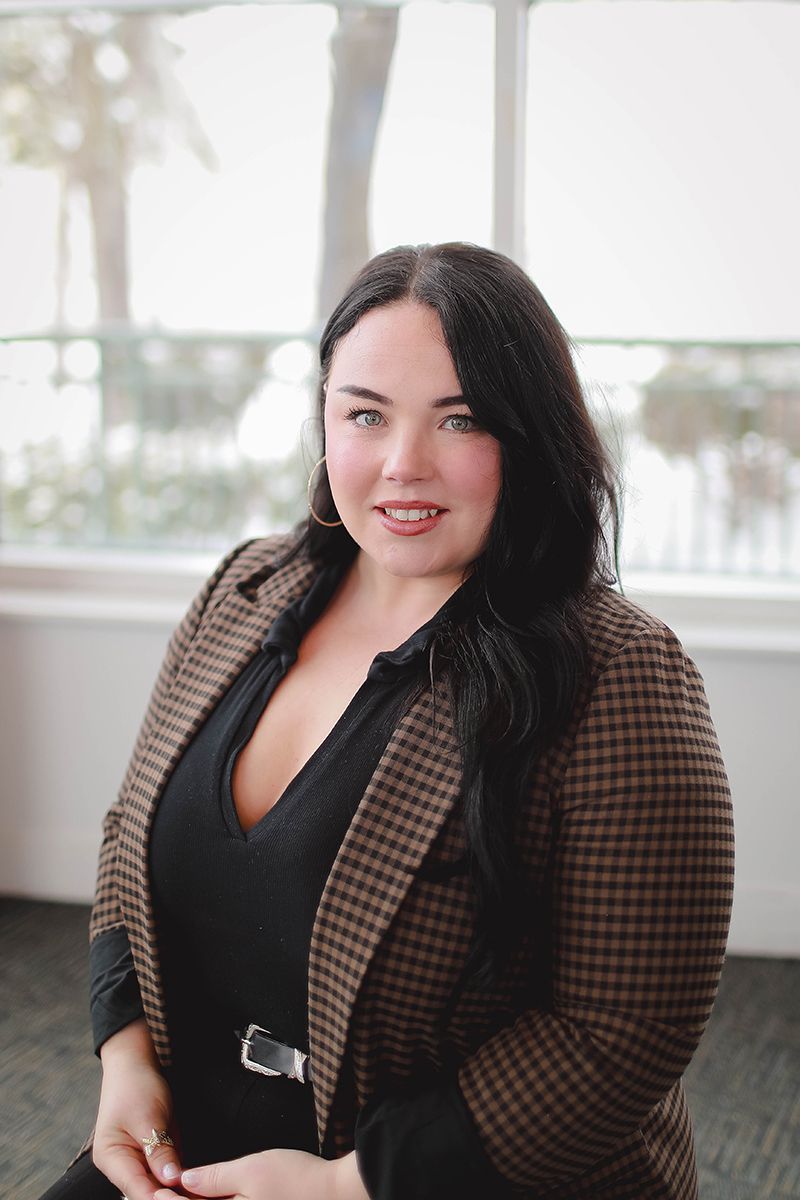 A woman in a green shirt and necklace is smiling for the camera.
