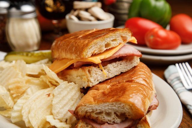 A ham and cheese sub sandwich on a plate with potato chips.