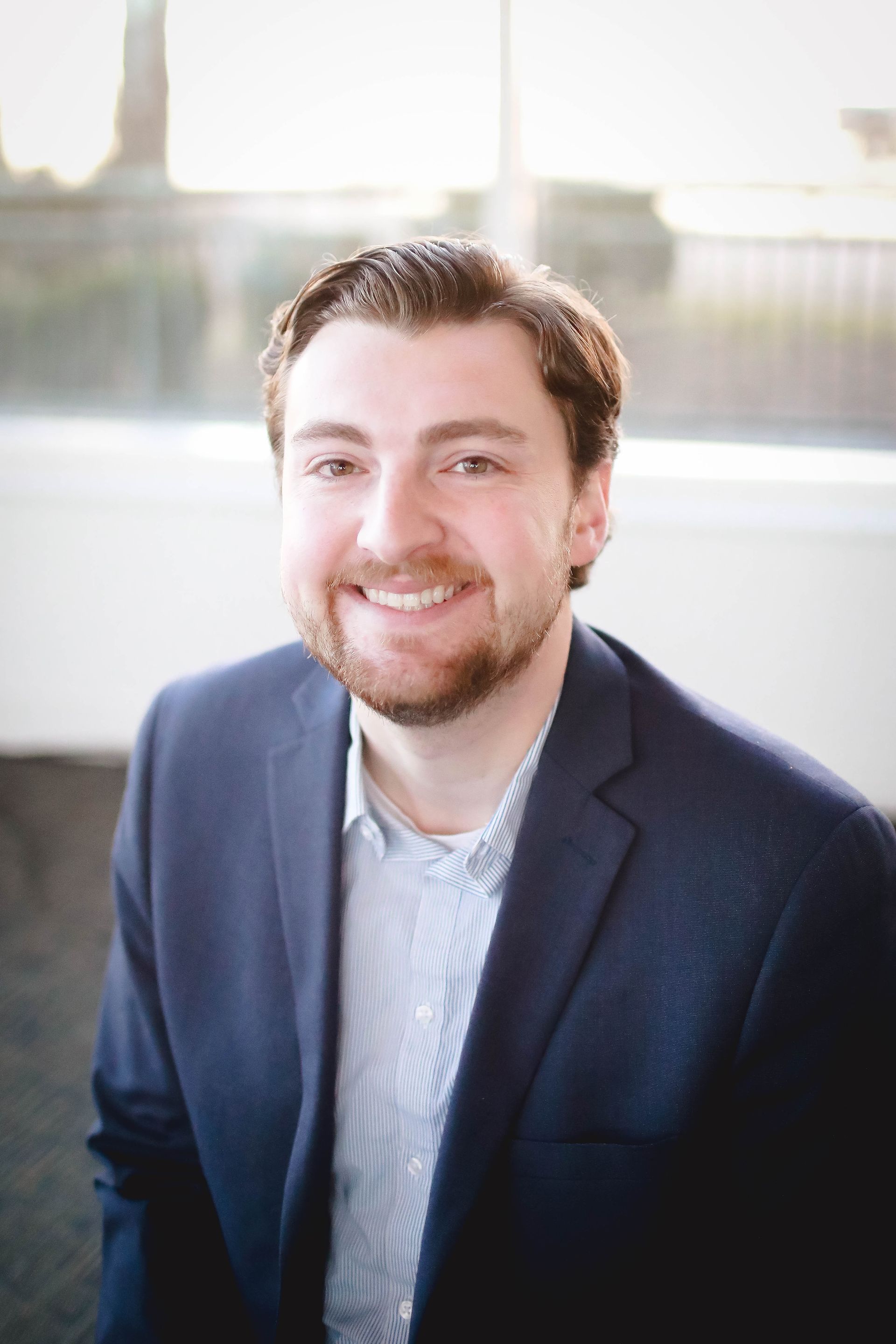 A man with a beard is smiling for the camera while wearing a polo shirt.