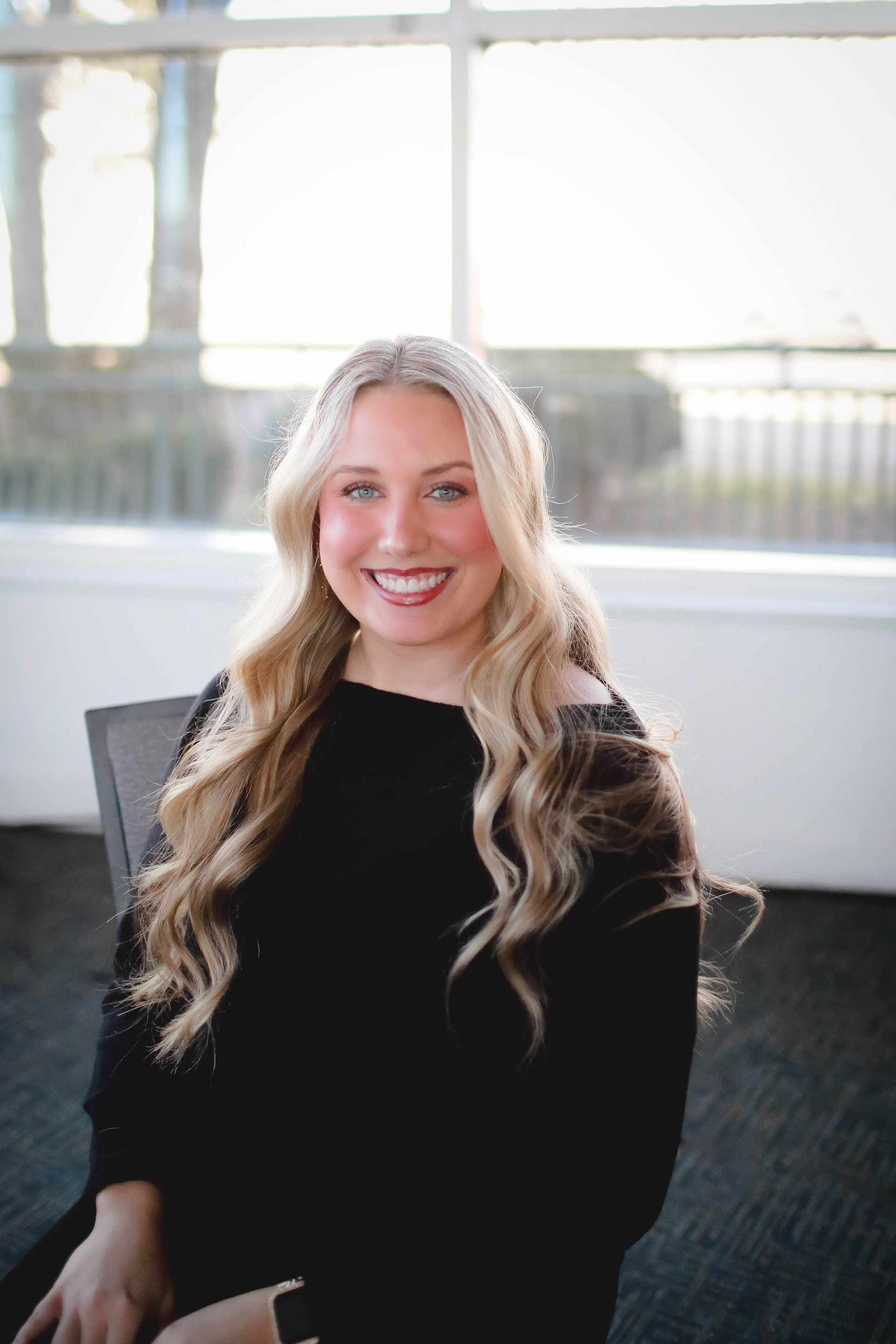 A woman with long blonde hair is wearing a white shirt and a black jacket.