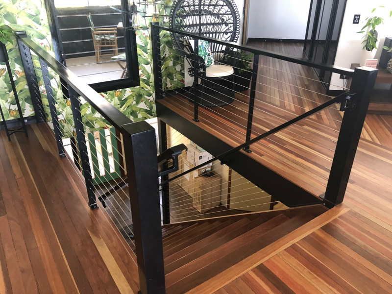 A staircase with a black railing and a wooden floor in a house. — DC Fencing In Wondunna, QLD