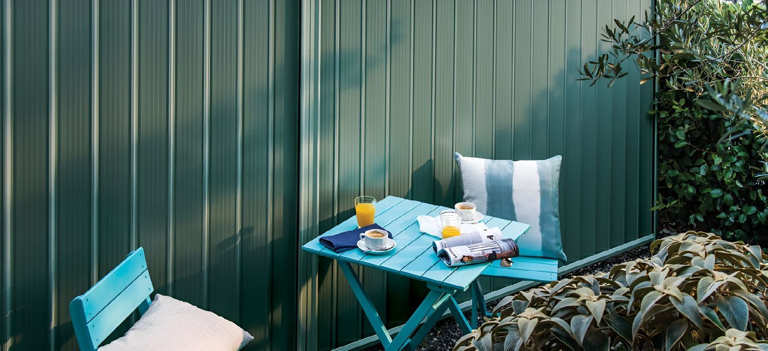 A Blue Table and Chairs Are Sitting in Front of a Green Fence — DC Fencing In Wondunna, QLD
