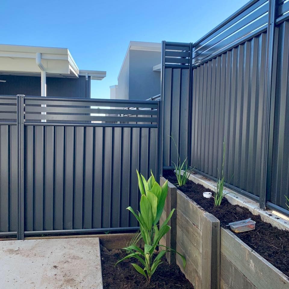 A Black Fence With a Planter in Front of It — DC Fencing In Wondunna, QLD