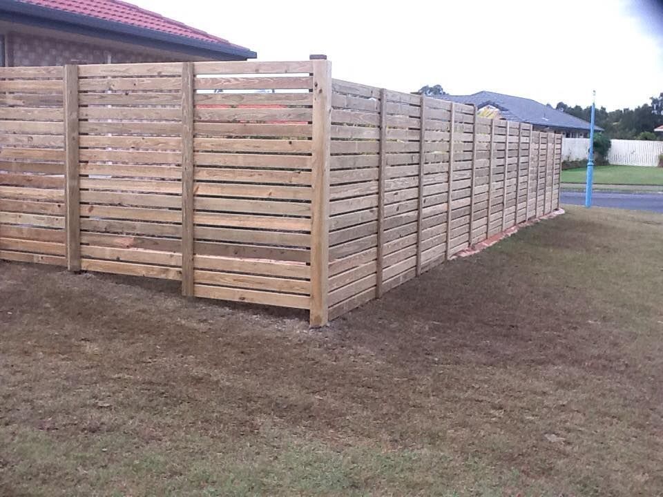A Wooden Fence With a House in the Background — DC Fencing In Wondunna, QLD