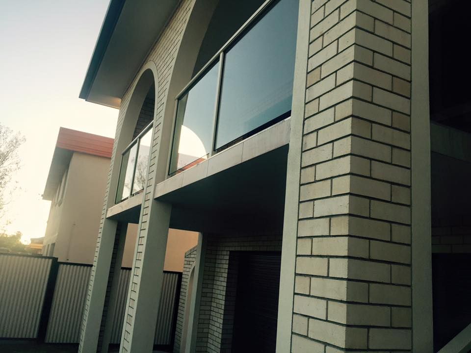 A White Brick Building With a Balcony and Stairs — DC Fencing In Wondunna, QLD