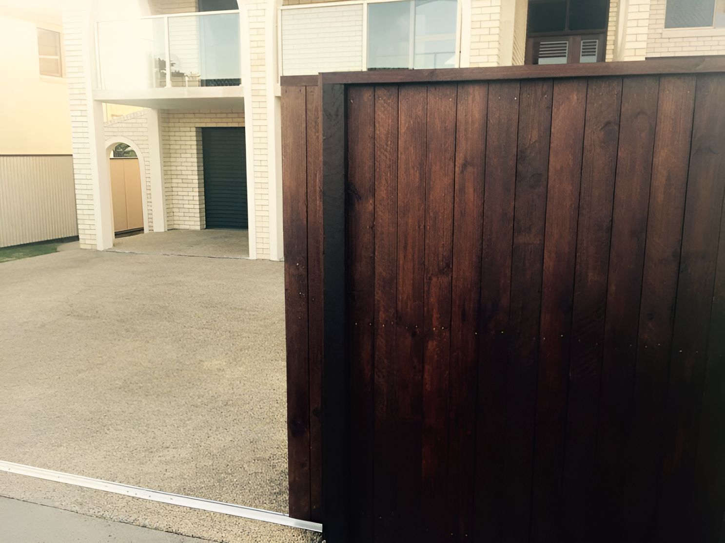 A Wooden Fence Surrounds a Driveway in Front of a House — DC Fencing In Wondunna, QLD