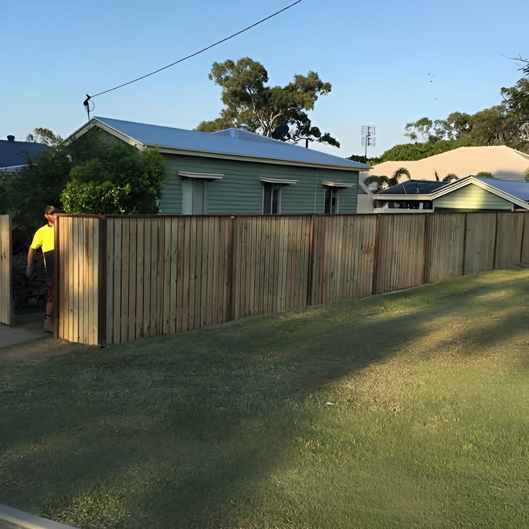 A Wooden Fence Surrounds a Grassy Yard in Front of a House — DC Fencing In Wondunna, QLD