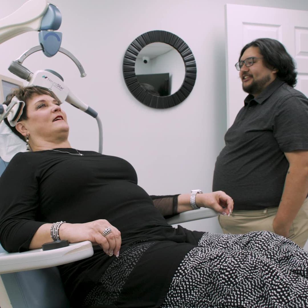 TMS therapy technician helps a patient in-office