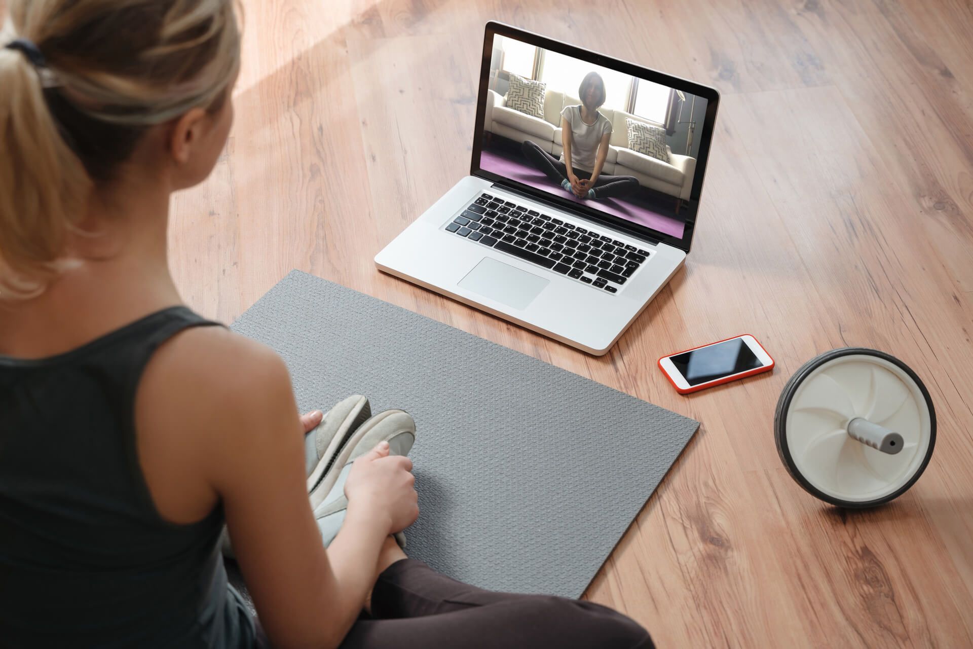 Woman attending virtual yoga class at home on a video conference.