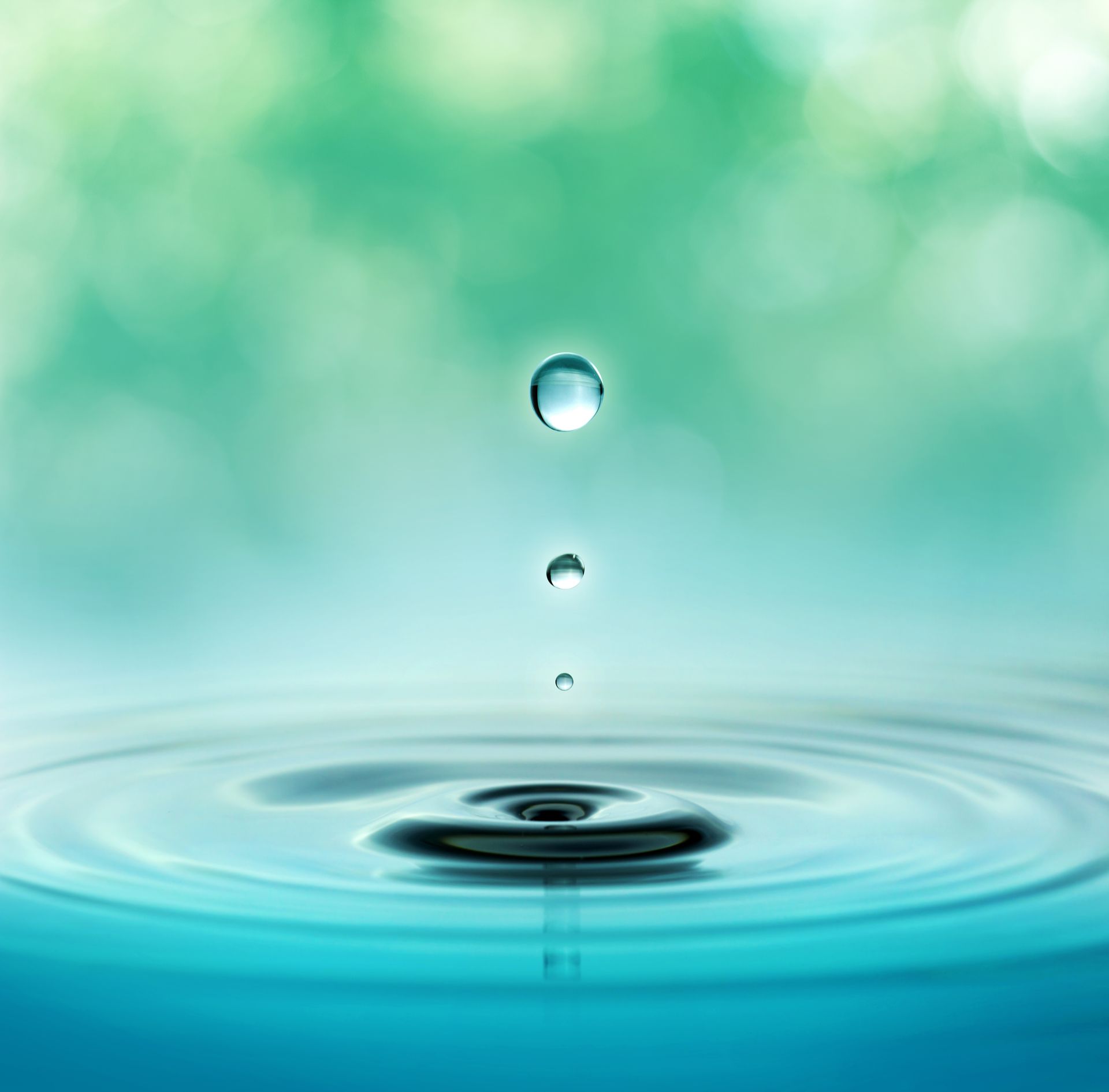 close up of three water droplets in a blurred green background