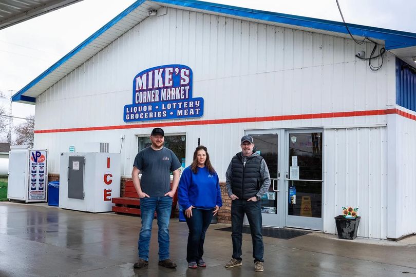 Three people are standing in front of a store.