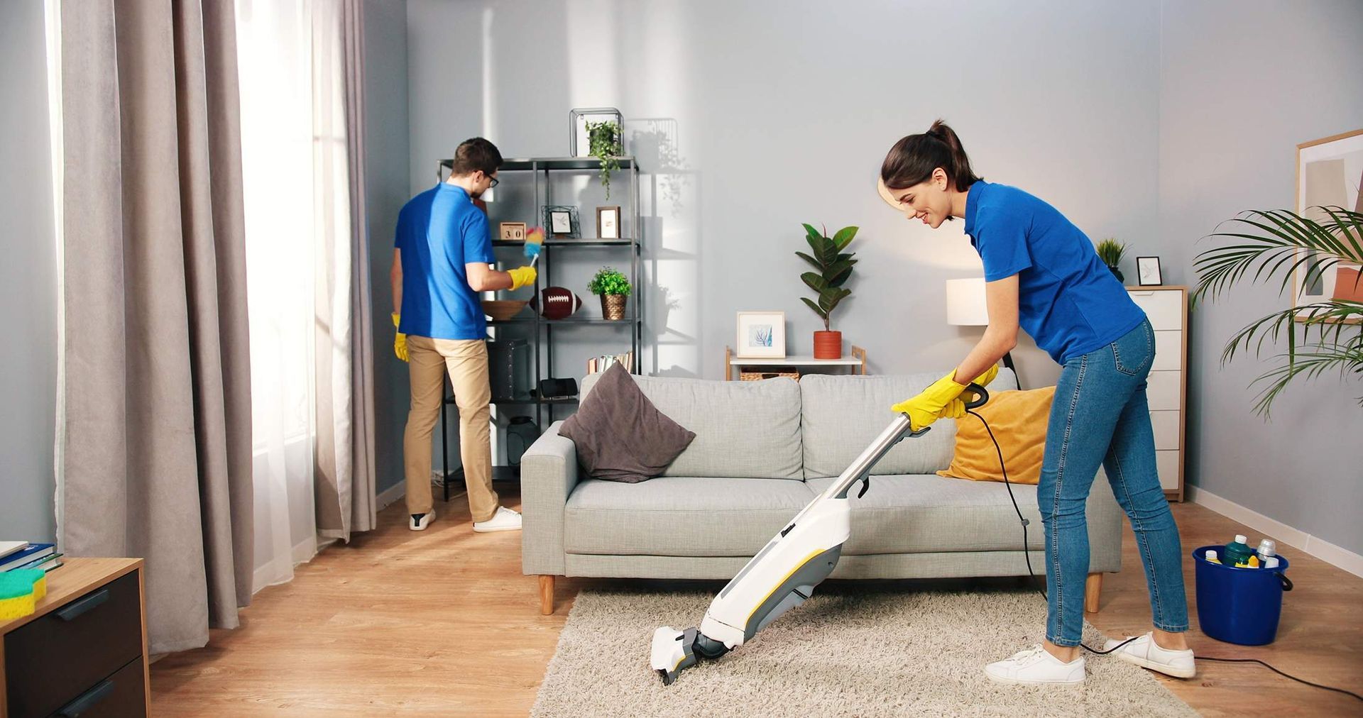 A woman is cleaning a living room with a vacuum cleaner.