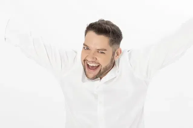 Un hombre con una camisa blanca levanta los brazos en el aire.