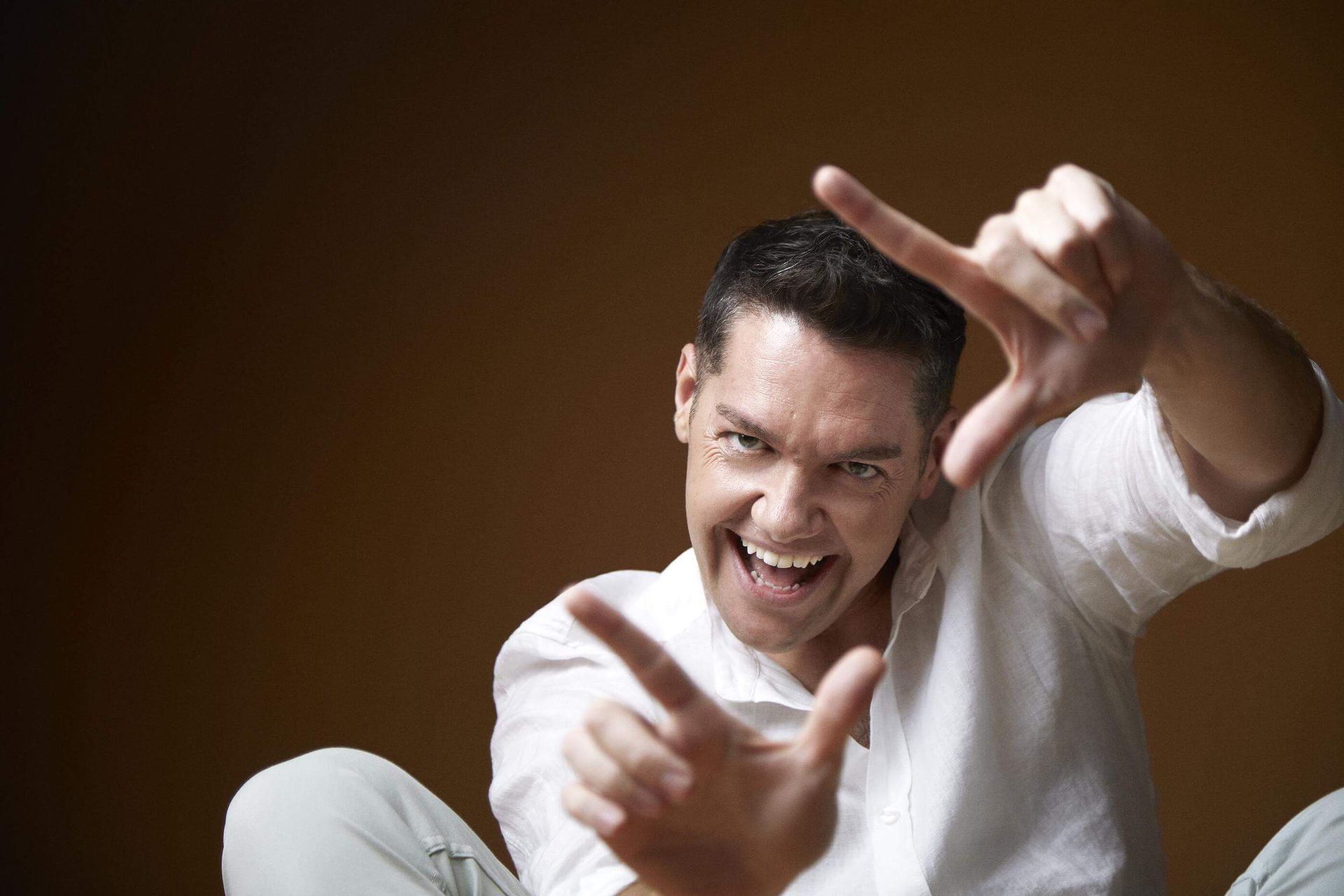 Un hombre con una camisa blanca está haciendo un marco con sus manos.