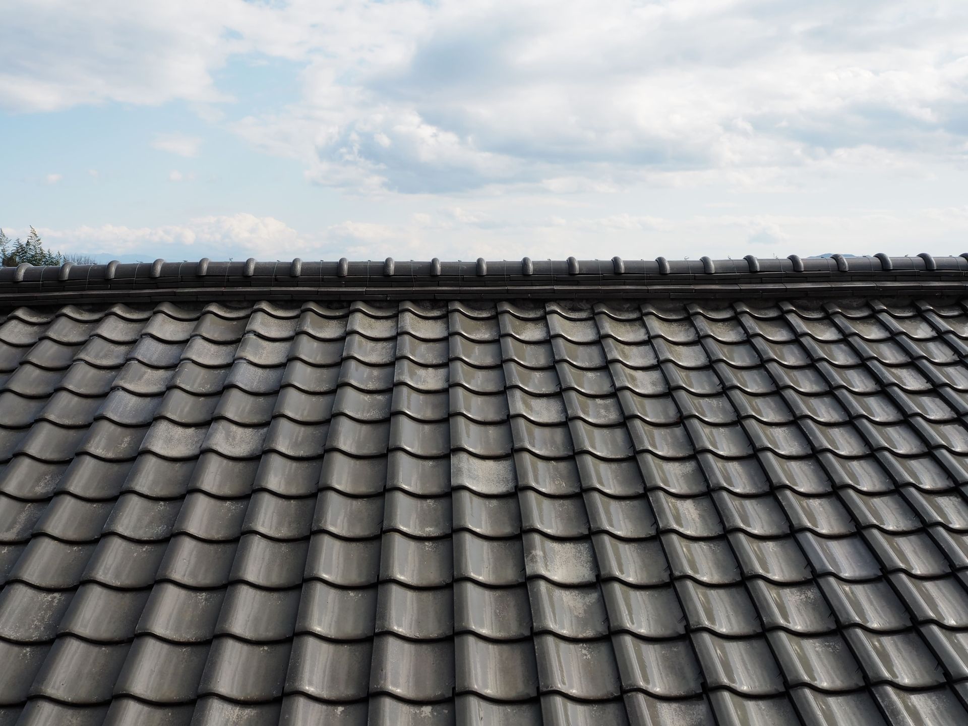 Dark gray tiled roof against a cloudy blue sky. — Boostn Pty Ltd in Glastonbury, QLD