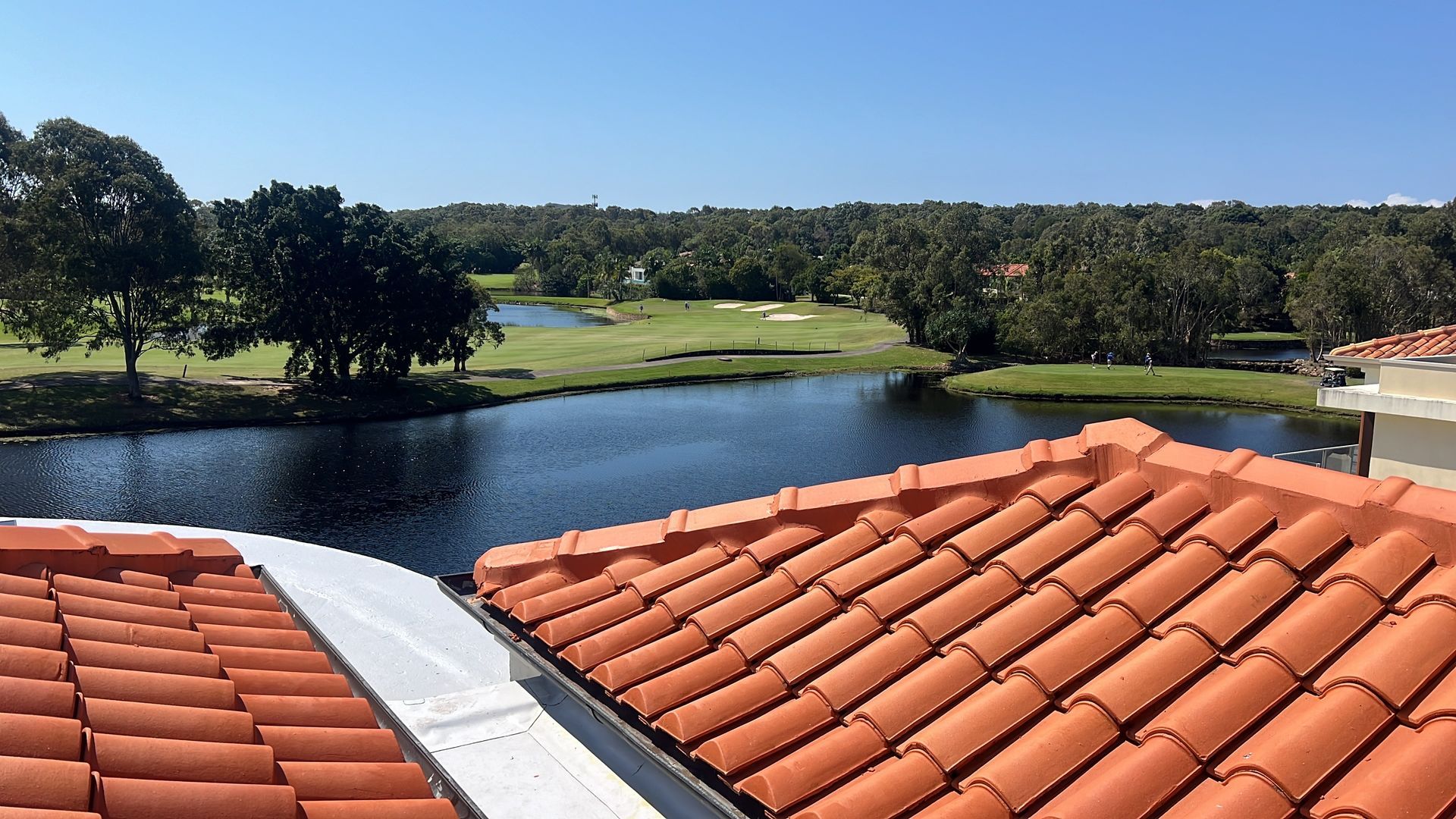 Red tile roof overlooking a lake, golf course, and trees under a blue sky. — Boostn Pty Ltd in Glastonbury, QLD