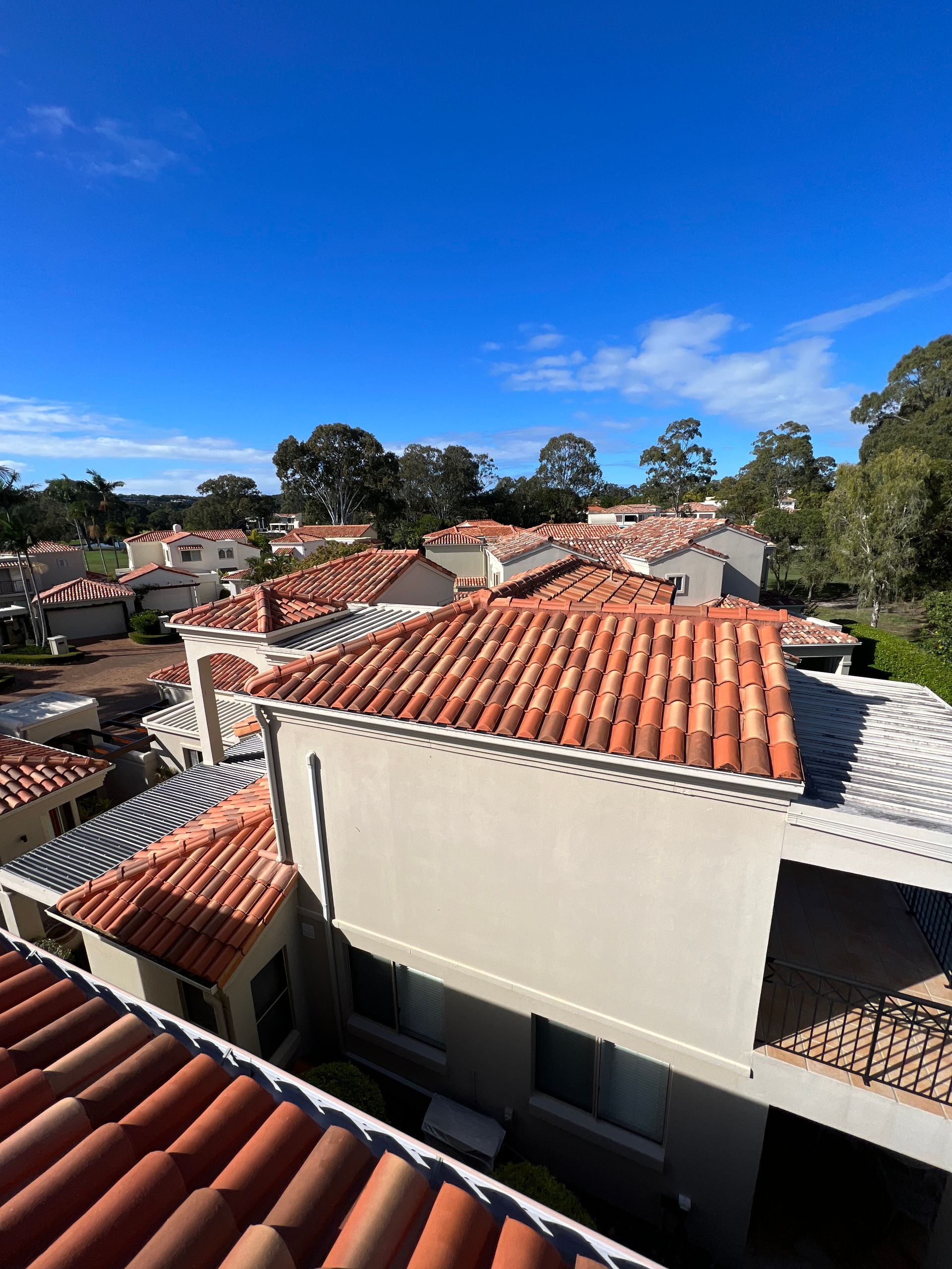 Red-tiled roofs and white buildings under a bright blue sky, likely a residential area. — Boostn Pty Ltd in Glastonbury, QLD