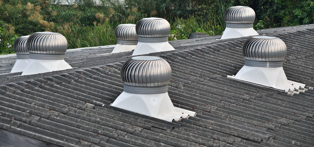 Several Silver Roof Vents on a Gray, Tiled Roof. Green Foliage in the Background — Boostn Pty Ltd in Glastonbury, QLD