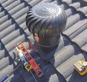 Black roof turbine on a tiled roof with tools nearby. — Boostn Pty Ltd in Glastonbury, QLD