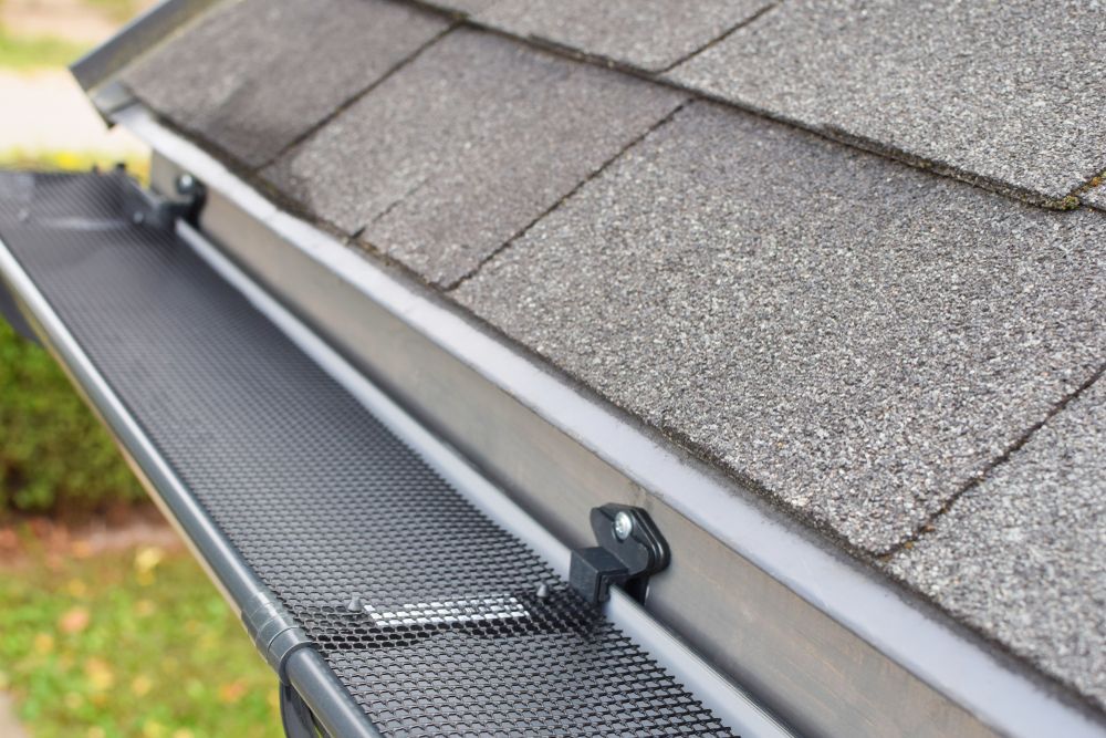 Gutter With a Black Mesh Cover Installed Along the Edge of a Gray Shingled Roof — Boostn Pty Ltd in Hervey Bay, QLD