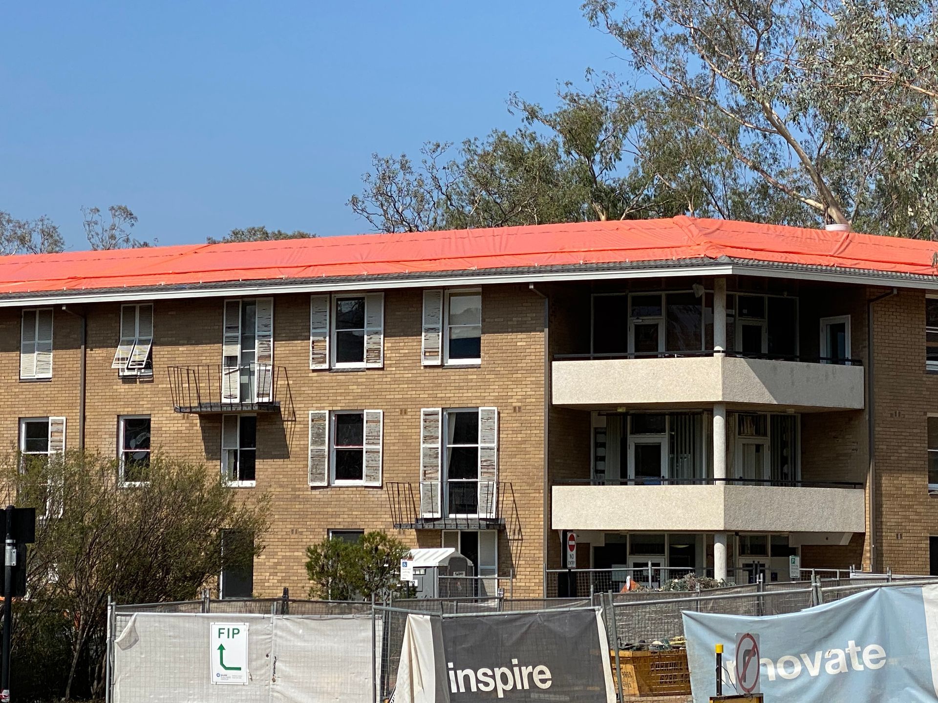 Brick apartment building with orange roof and open shutters; a construction site in front. — Boostn Pty Ltd in Glastonbury, QLD
