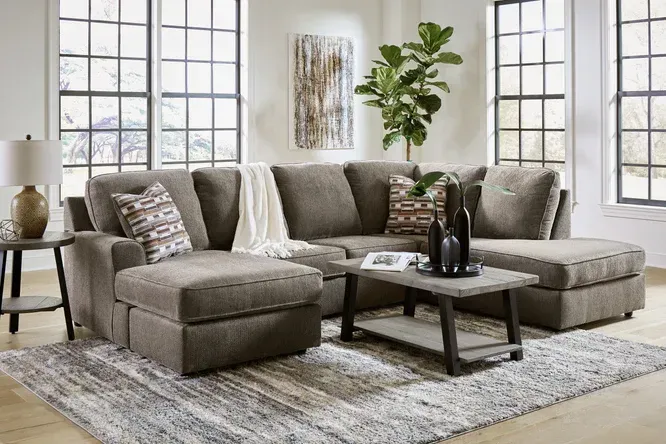 A sectional sofa with chaises, coffee table, and area rug in a living room with large windows.