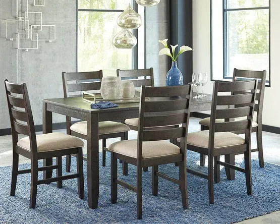 Dining table with six matching chairs in a modern room, set on a blue rug, overhead lights.