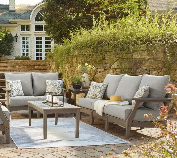 Outdoor seating set with gray cushions and coffee table on a patio.