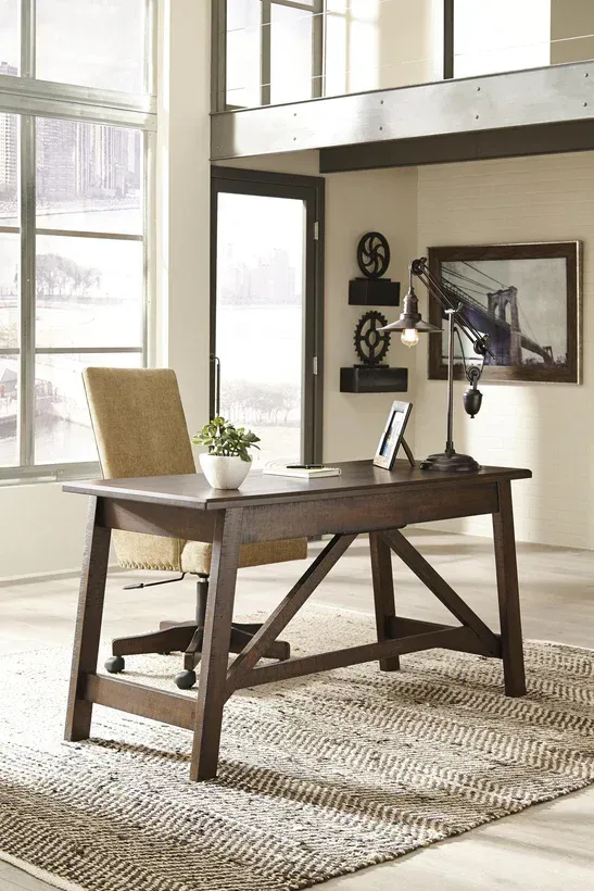 Wooden desk and chair in a well-lit home office, with window view and decor.