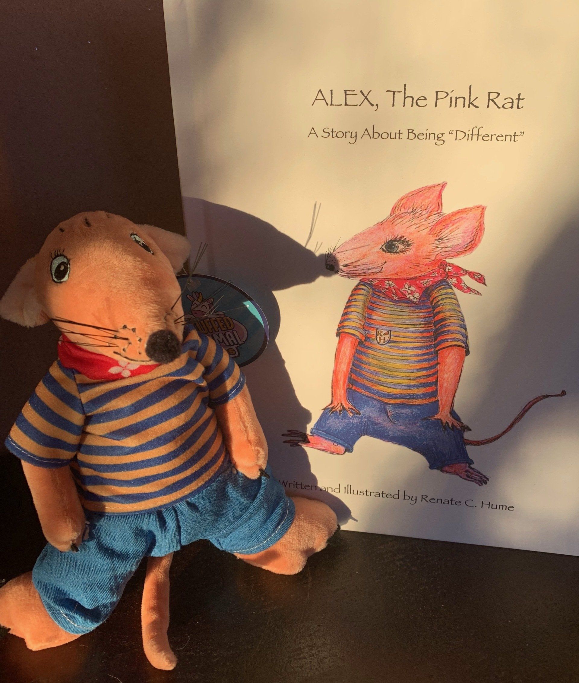 ALEX, The Pink Rat book with plushie toy sitting next to it