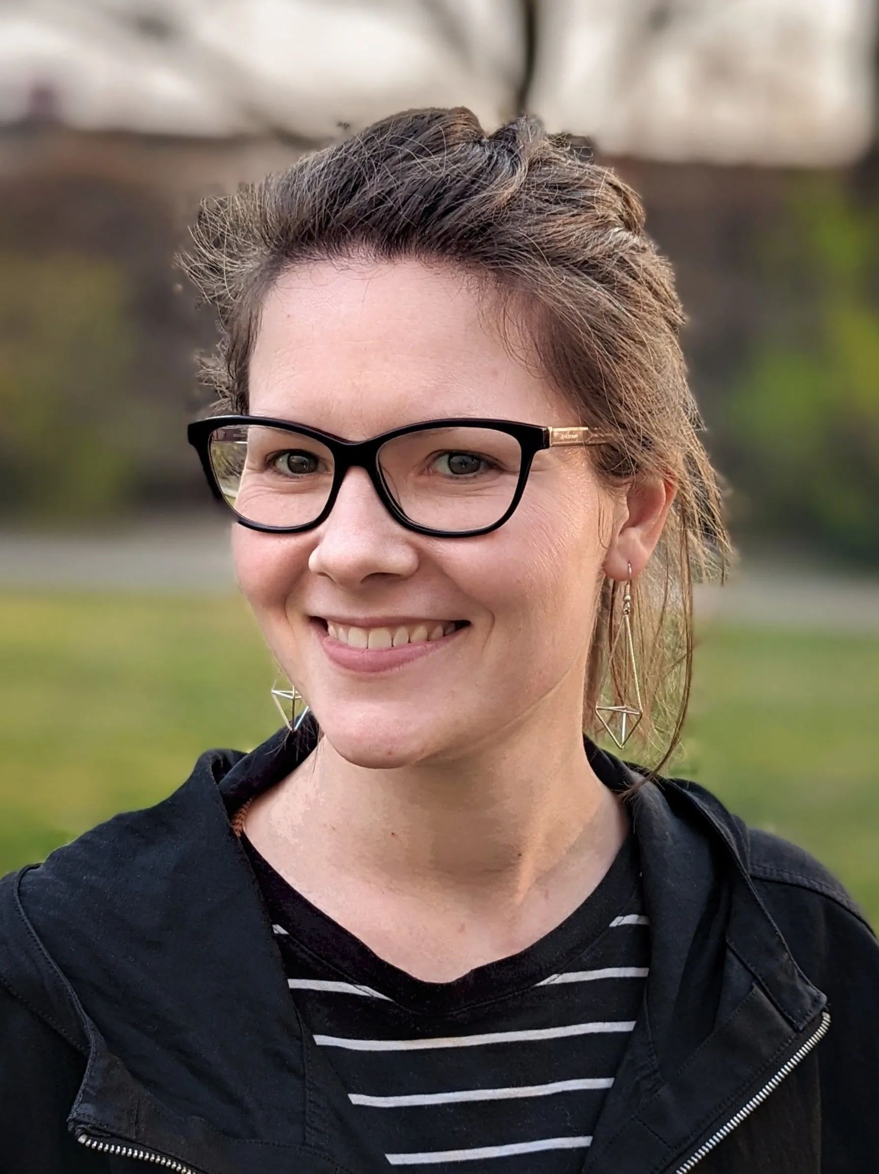 Eine Frau mit Brille und schwarzer Jacke lächelt in die Kamera.