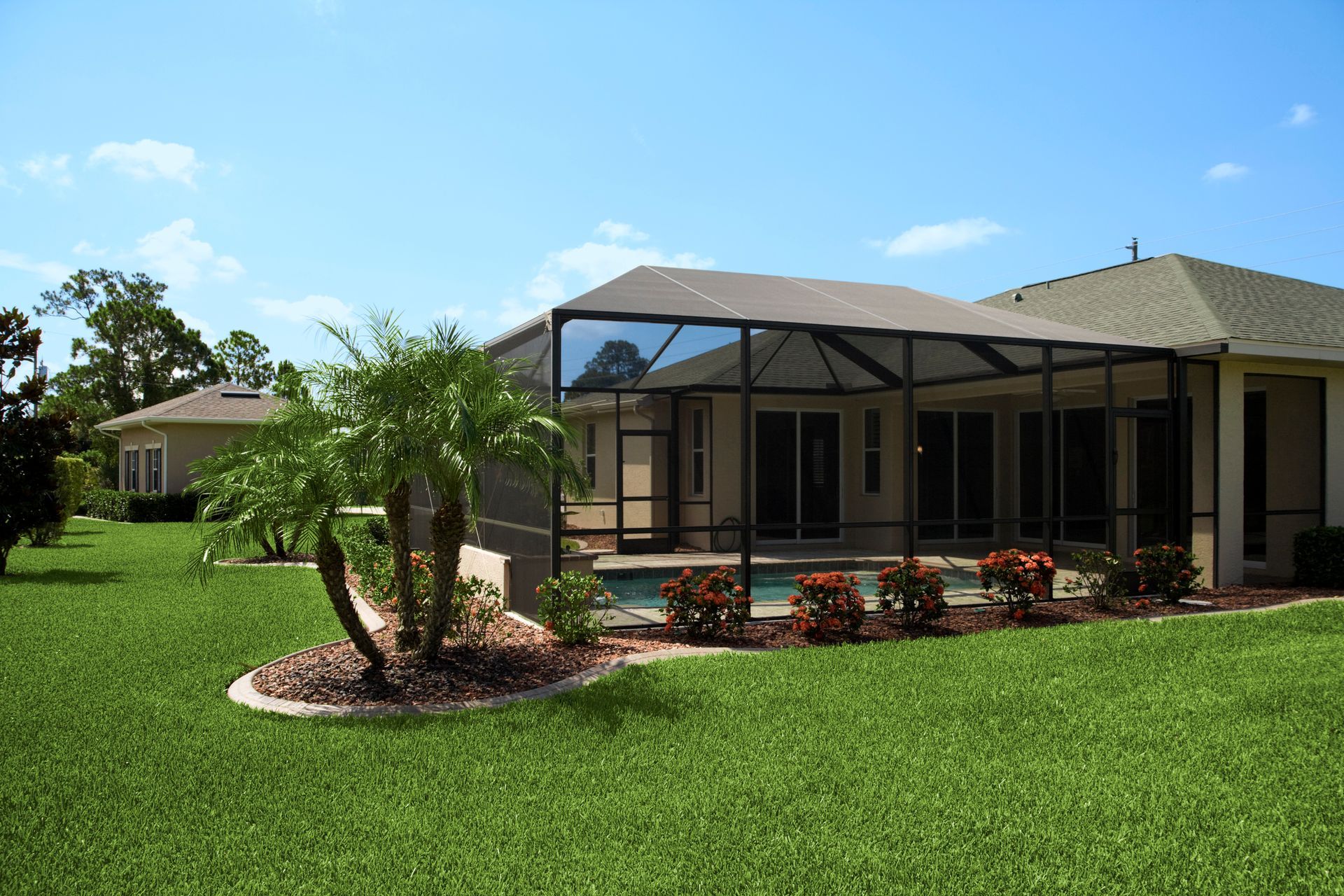 Backyard with screened pool enclosure, green lawn, palm trees, and clear blue sky.