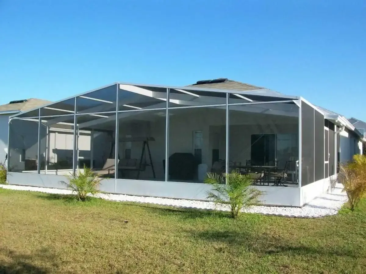 A screened-in patio attached to a house with clear blue sky in the background.