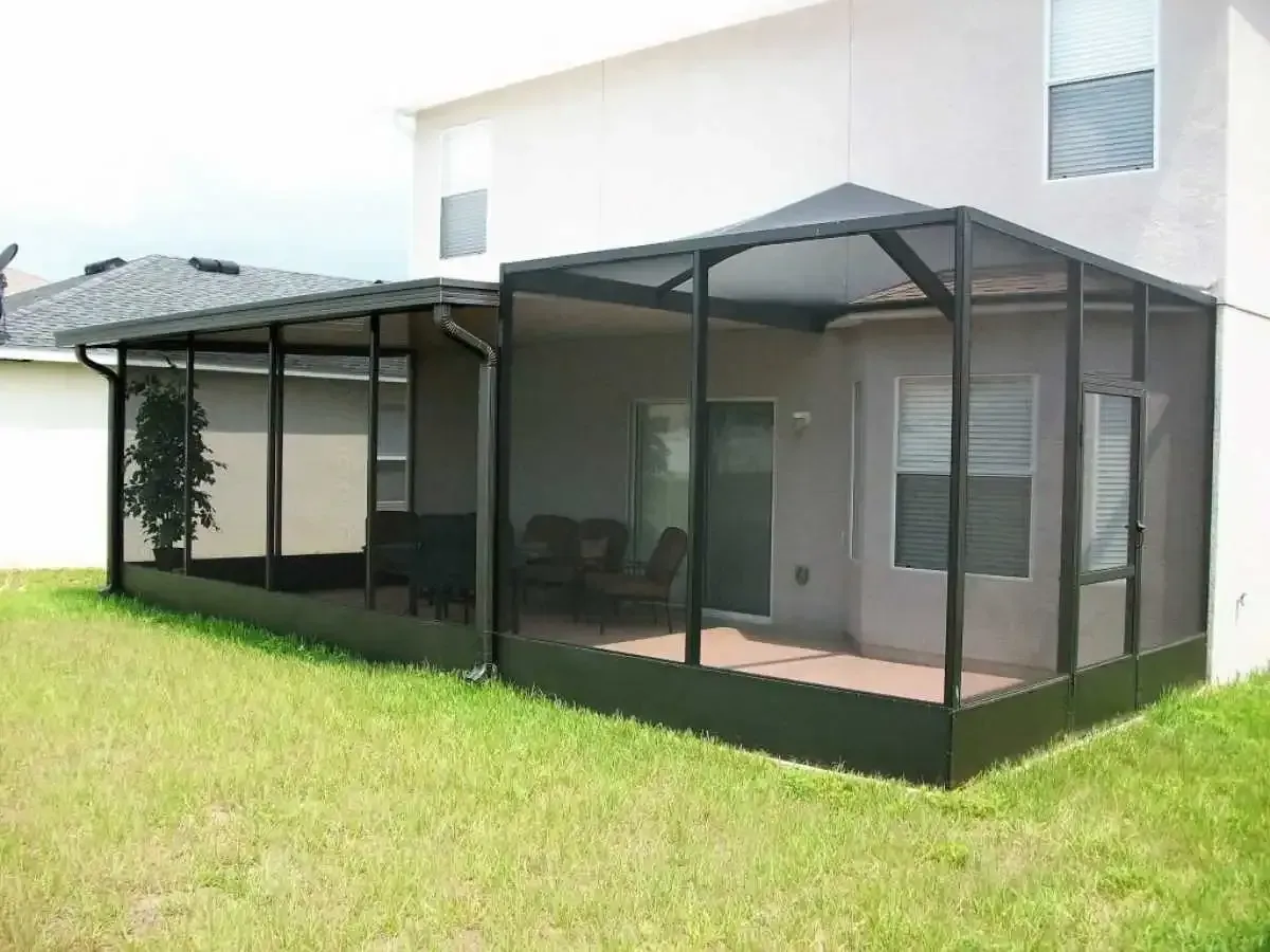 Screened-in patio extension attached to a two-story beige house; black framing, green lawn.