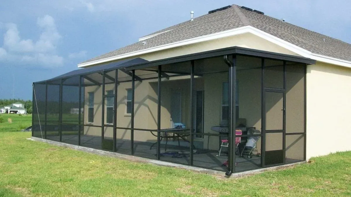 Black screened-in porch attached to a light-colored house. Green grass surrounds.