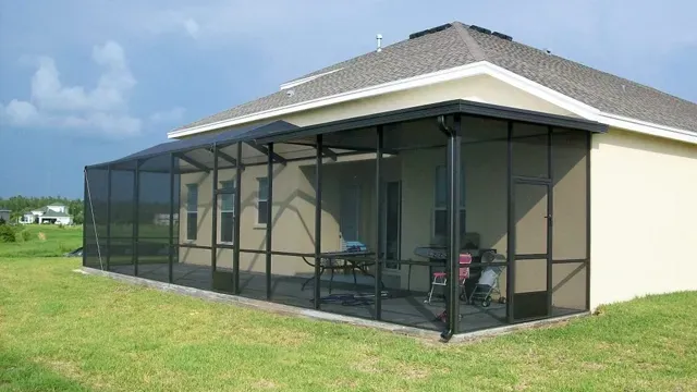 Black screened-in patio attached to a beige house, set on green grass under a partly cloudy sky.
