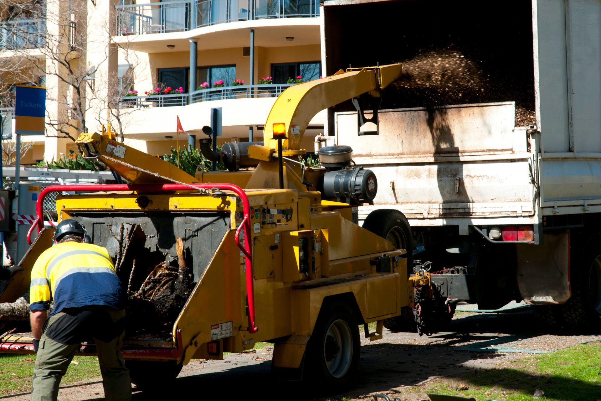 A man is working on a tree chipper next to a truck.