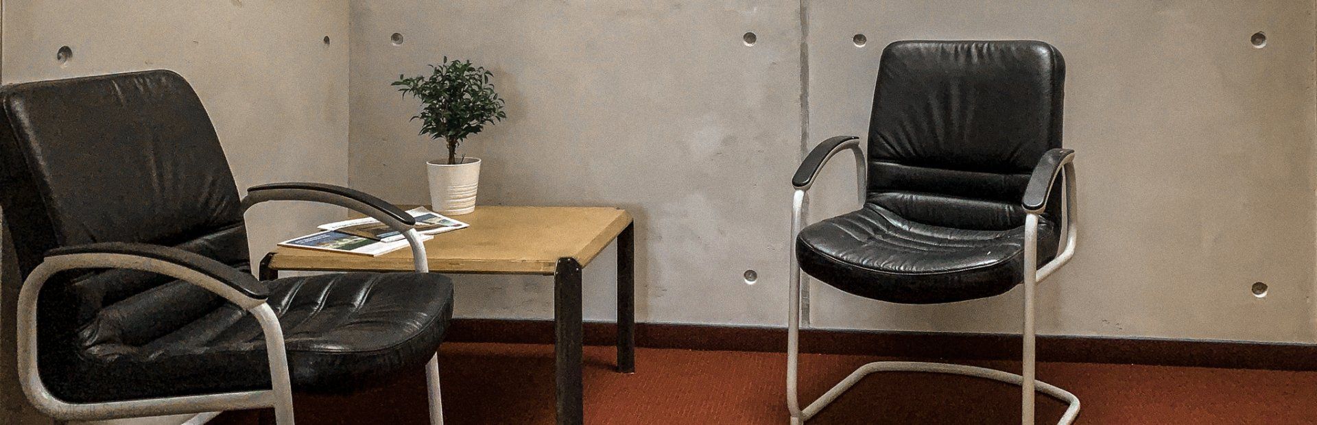 Mikrozement Wand in Betonoptik in einem Büro von rauMKult Sichtbeton, Schwarze Stühle und ein Tischaus Holz stehen davor